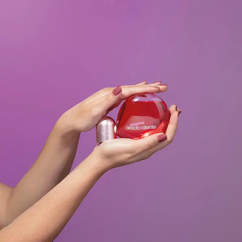 Flacon van Sempre Desobediente Eau de Parfum in kleurrijk design tegen een paarse achtergrond