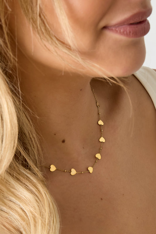 Ketting roestvrijstaal met hartjes in de kleur goud gedragen door vrouw