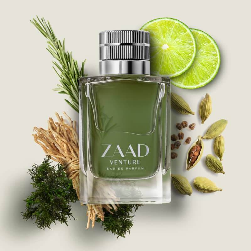 Zaad Venture Eau de Parfum flacon omringd door verse limoen, kardemompeulen, rozemarijn, vetiver en mos – ingrediënten van een houtachtig frisse herengeur.