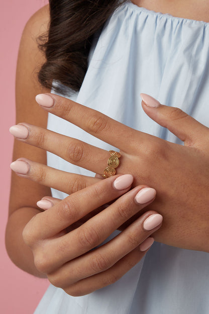Verstelbare ring met een twisted vorm in de kleur goud, gedragen om middelvinger