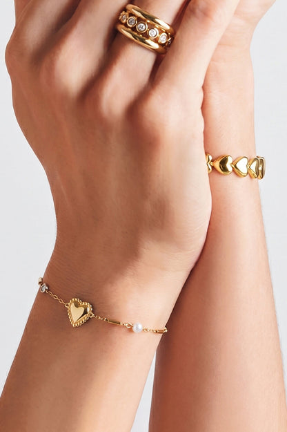 Gouden stainless steel armband voor dames met hart en parels gedragen om de pols