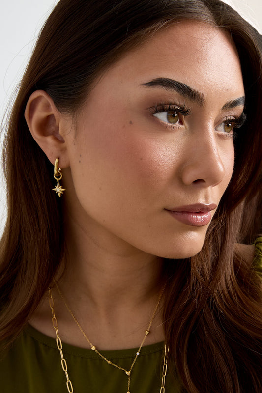 Oorbellen met vallende ster gedragen door een model. Gemaakt van stainless steel in de kleur goud
