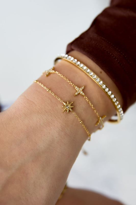 Waterproof gouden armband vallende ster gedragen om pols in combinatie met andere armbanden